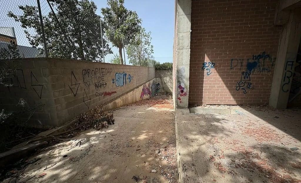 Внешний проход вдоль здания, земляное основание и кирпичные стены.