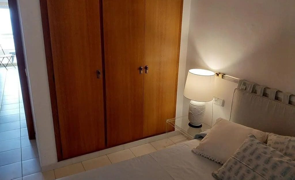 Спальня с двуспальной кроватью и встроенным деревянным шкафом.