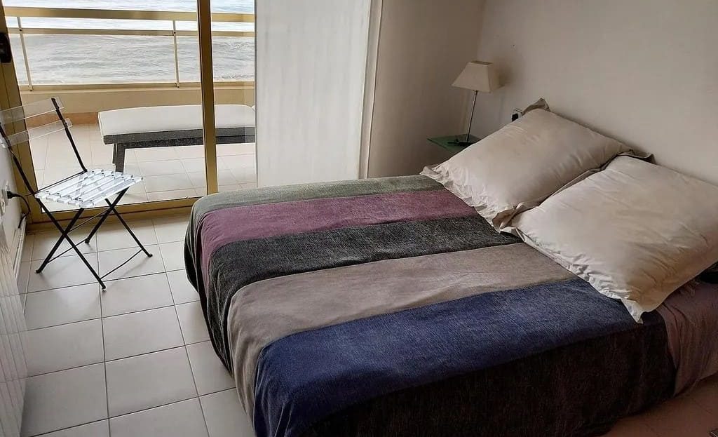 Спальня с двумя односпальными кроватями и видом на море через окно.