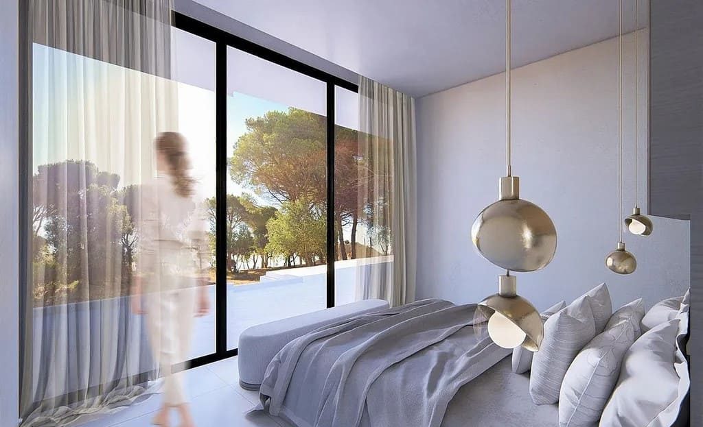 Спальня с панорамным окном и видом на зелёный участок.