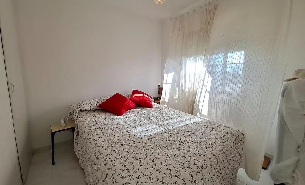 Спальня с двуспальной кроватью и светлым интерьером.