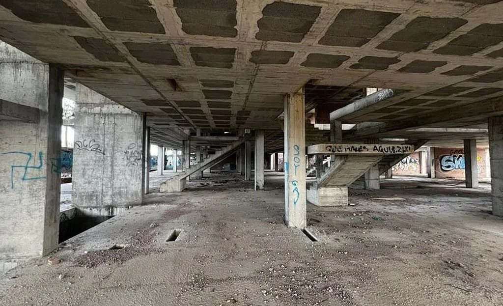 Подземный или нижний уровень с бетонными колоннами и грунтовым полом.