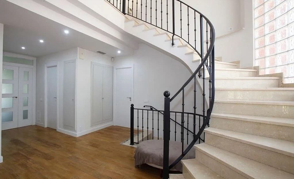 Лестничный холл с винтовой лестницей и светлым интерьером.