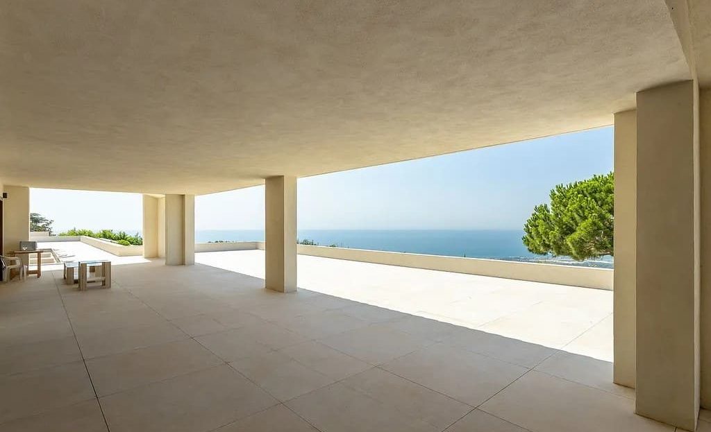 Крытая галерея с выходом на открытую террасу и морской пейзаж.