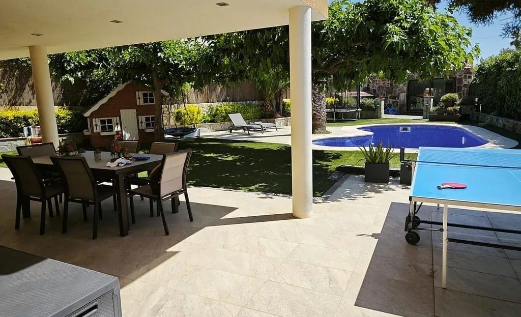Терраса дома в Испании с обеденной зоной, видом на сад и частный бассейн.