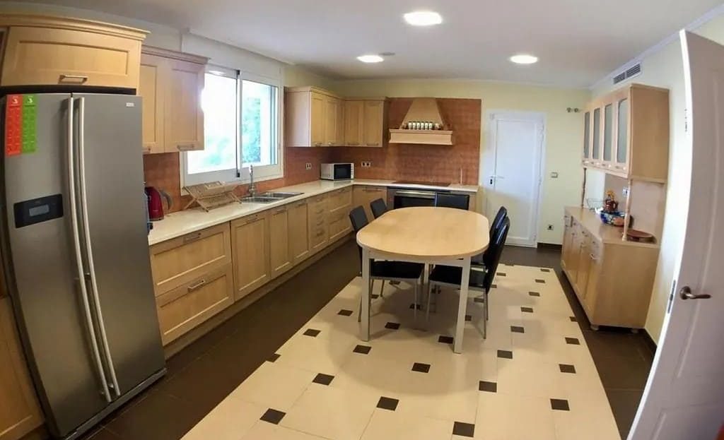 Просторная современная кухня, полностью оборудованная техникой, с обеденным столом.