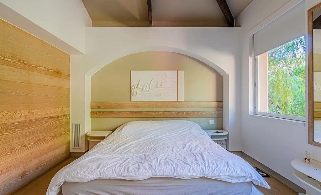 Светлая спальня в средиземноморском стиле со сводчатым потолком и видом на зелень