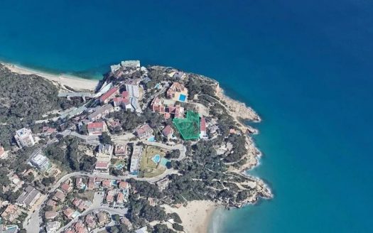 Вид с воздуха с меньшей высоты на мыс Кап Салоу. Снимок подчеркивает близость жилых зданий к обрывистому берегу, небольшие бухты с пляжами и густую зелень вокруг объектов.