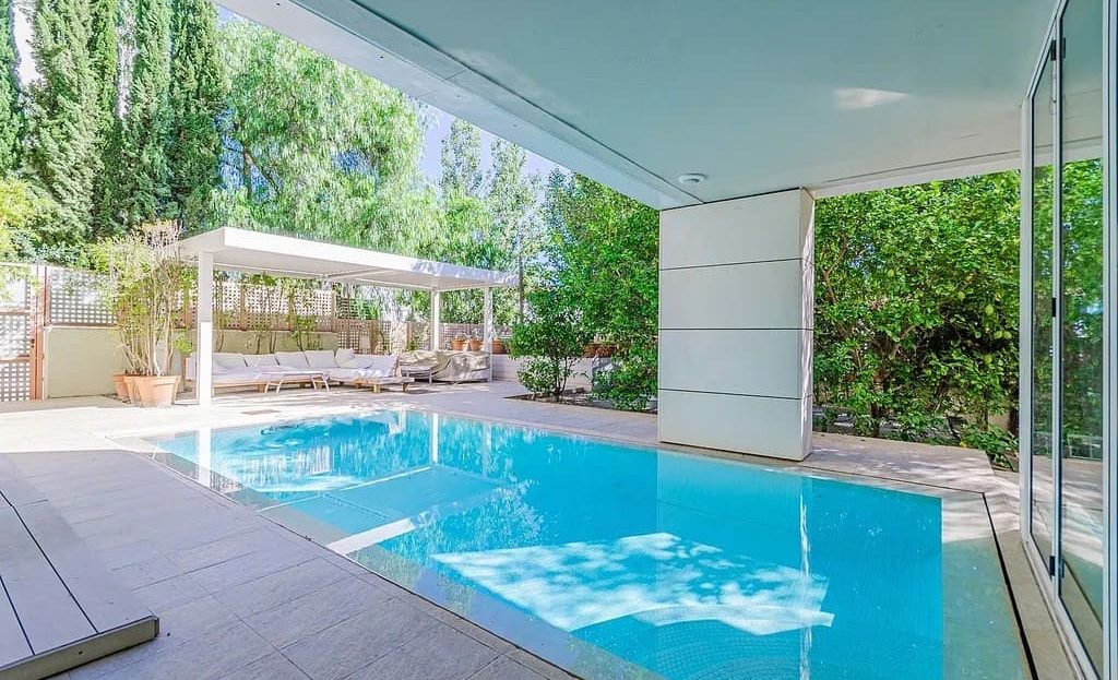 Частный бассейн с деревянной террасой на многоуровневом участке дома в Барселоне.