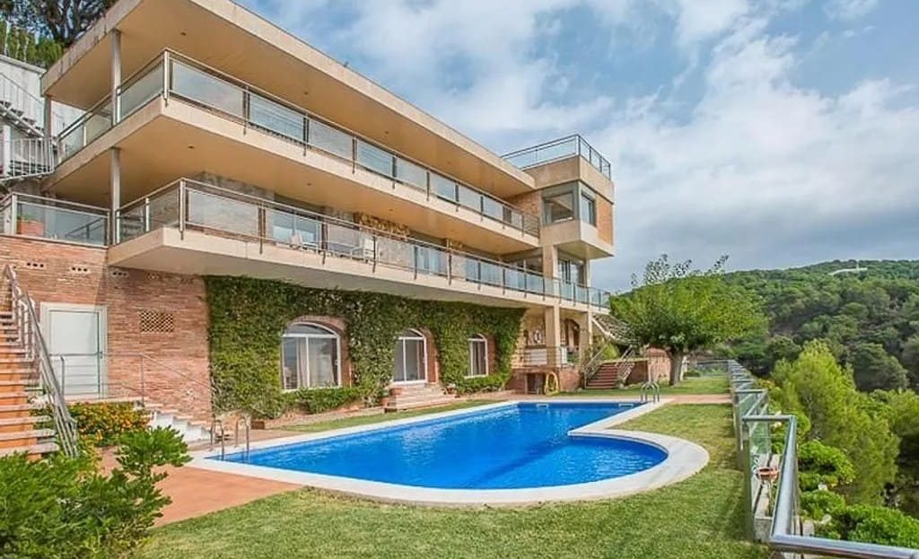 Фасад трехэтажной виллы со стороны бассейна и ухоженного зеленого сада.