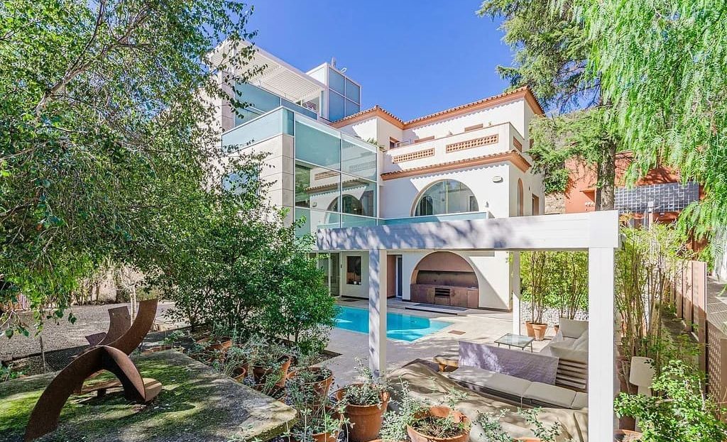 Зона отдыха у бассейна в ухоженном средиземноморском саду частного особняка.