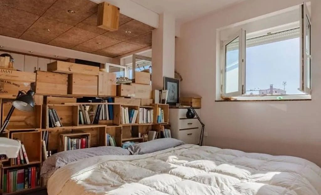 Уютная спальня в таунхаусе Таррагоны с книжными полками и натуральным светом.