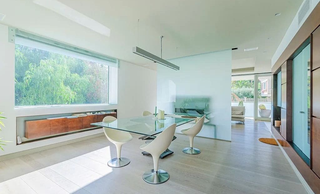 Просторная столовая с современным столом на 6 персон и видом на сад через панорамное окно.